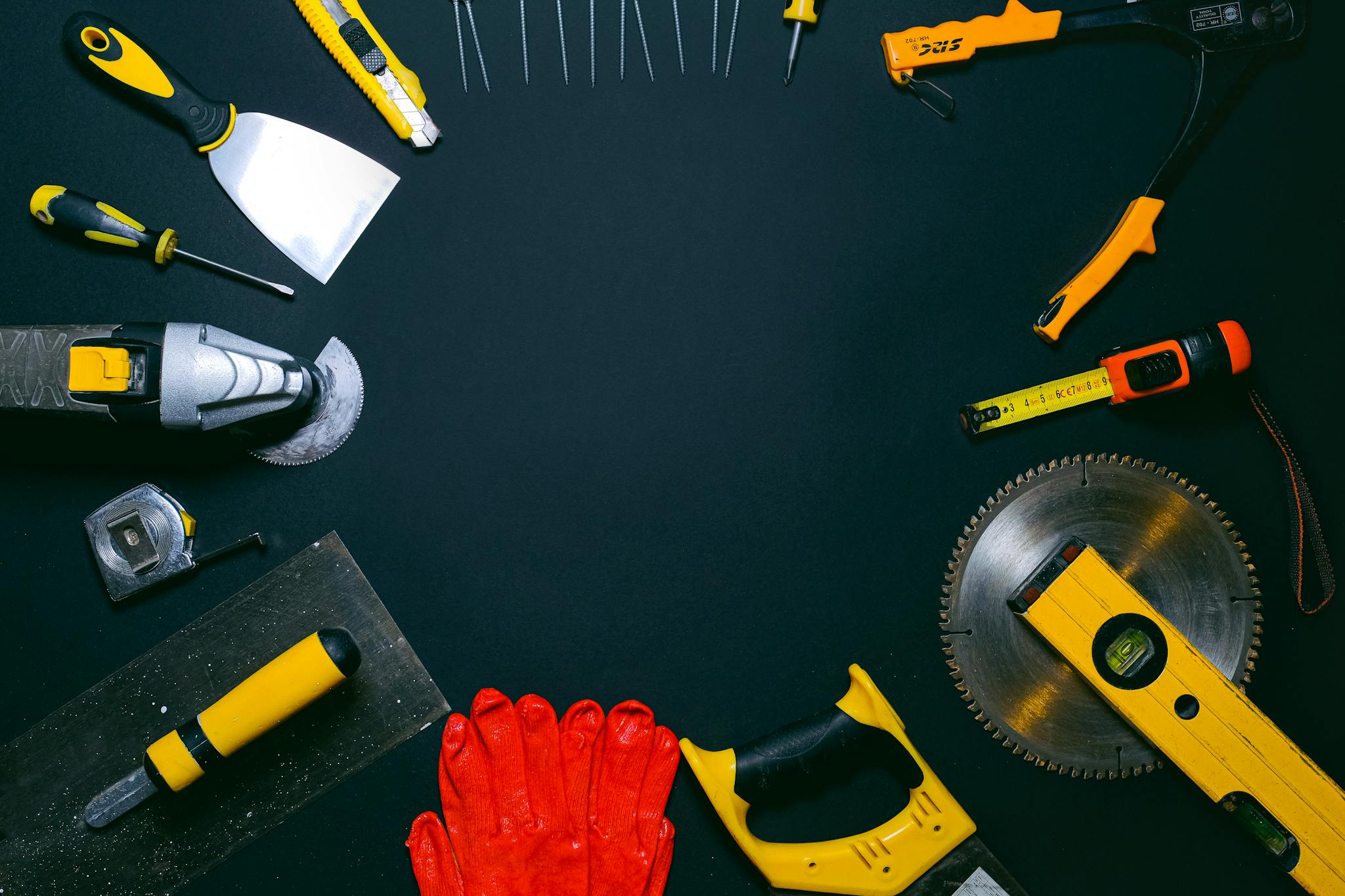 A collection of hand tools laid out on a dark surface, perfect for construction themes.