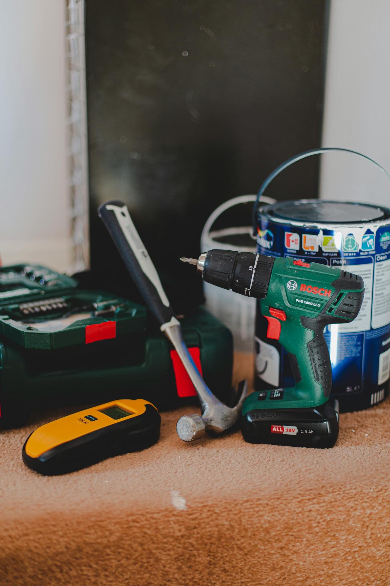 A selection of essential tools for home improvement projects, featuring a drill, hammer, and paint supplies.